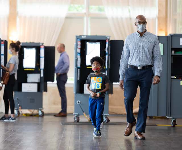 A black man is walking with his son as they leave a polling station after casting a ballot.
