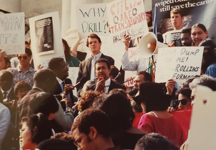 A crowd of people with environmental justice signs, standing on stairs
