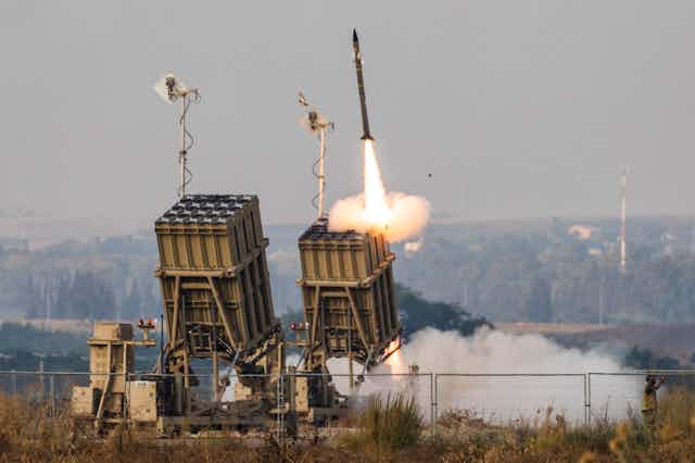a missile flies from one of two box-like structures in an open field