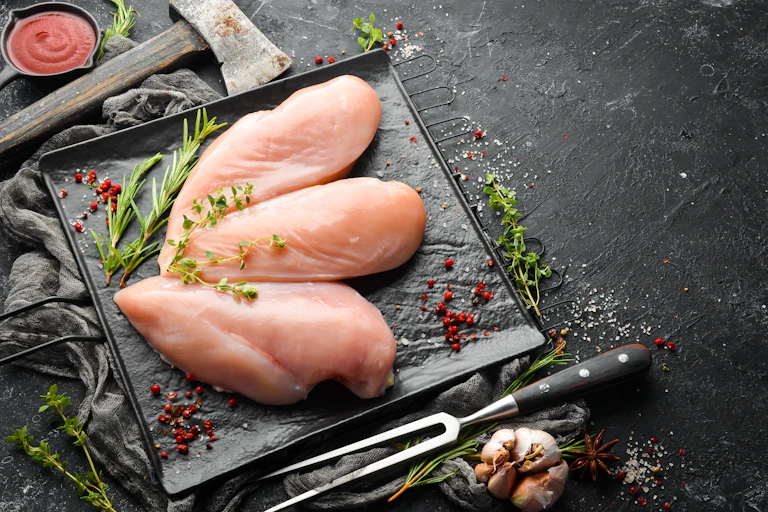 Raw chicken sits on a baking tray.