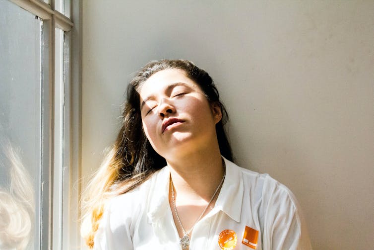 Fatigued woman rests her head against a wall