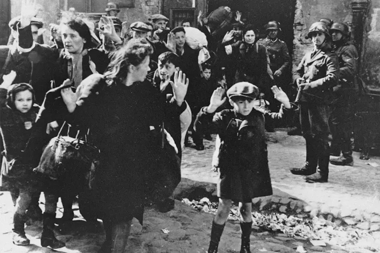 Jewish people being escorted from the Warsaw ghetto by German soldiers