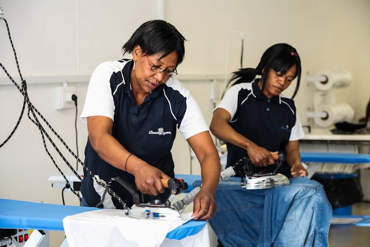 Women ironing clothing in a laundromat dry cleaning service.