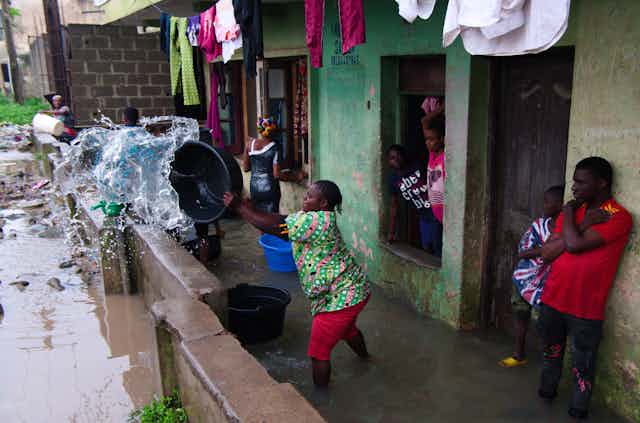 A woman removes water from her house after heavy rains 