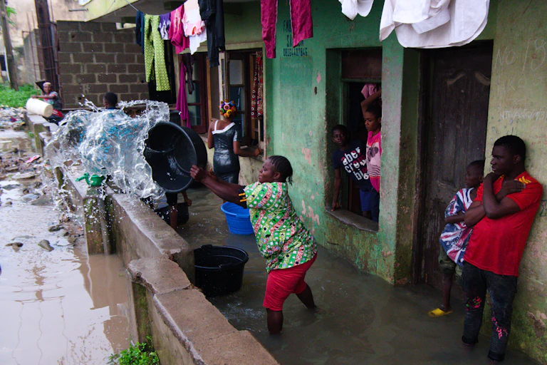 A woman removes water from her house after heavy rains