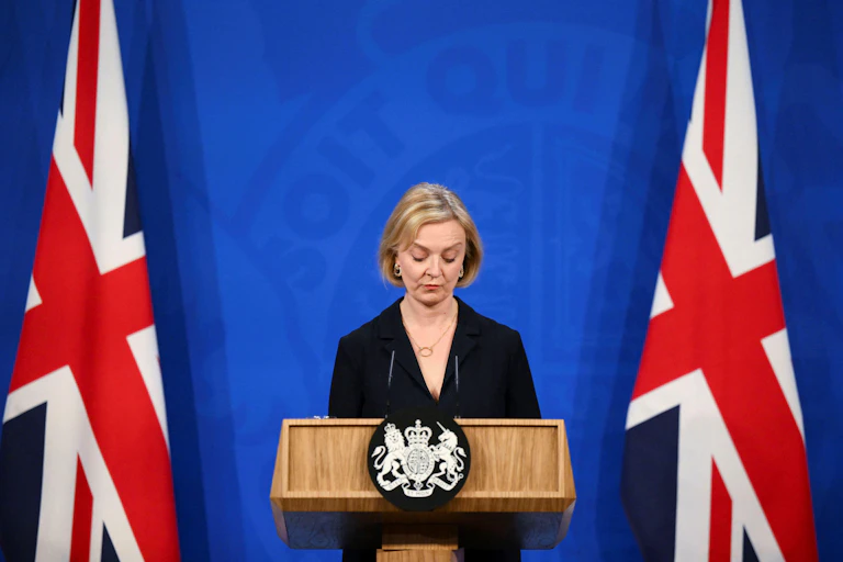 Liz Truss de pie entre dos banderas de Reino Unido.