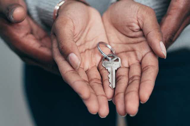 hands holding a house key