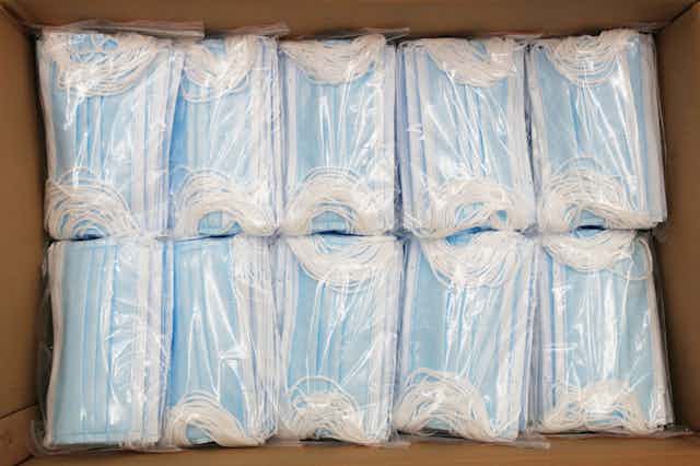 Open cardboard box of packaged surgical masks