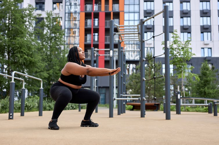 A person does squats in the park.