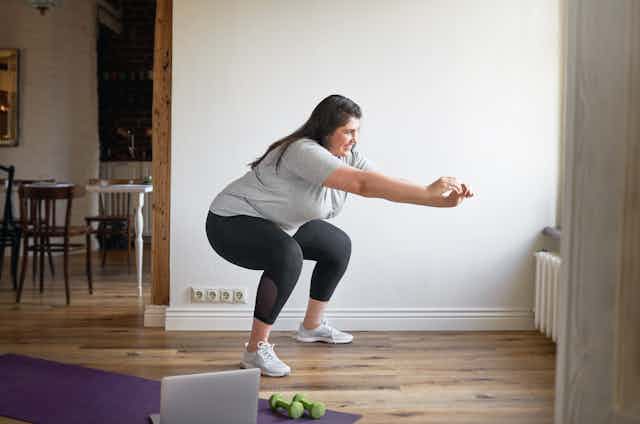 A woman does squats at home.