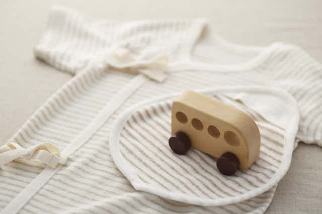 baby clothes laid out with wooden toy