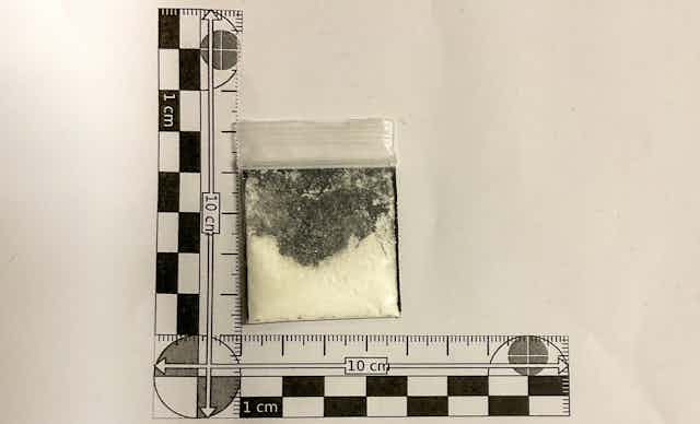 A plastic bag with a white powder in it with scale measure next to it