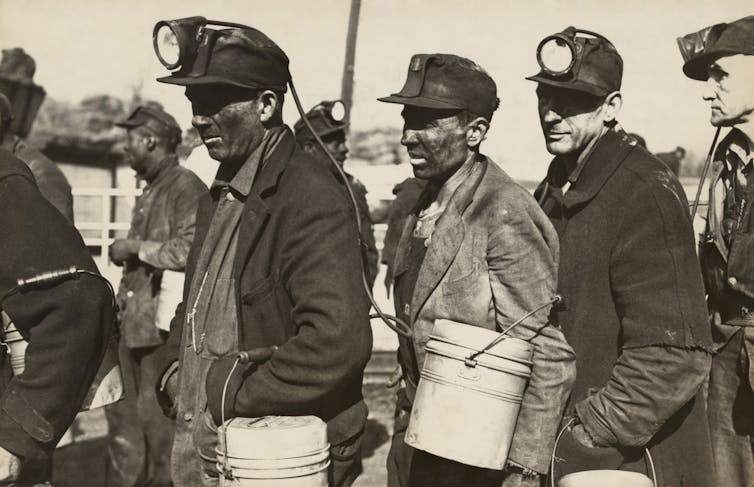 A black-and-white photo of coal miners in a queue.