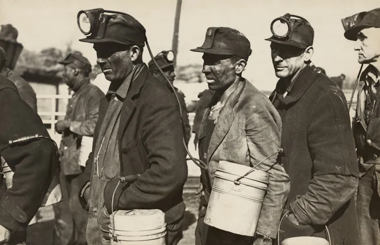 A black-and-white photo of coal miners in a queue.
