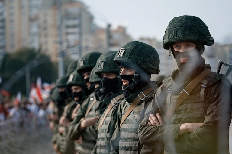 Riot police wearing green helmets in a line.