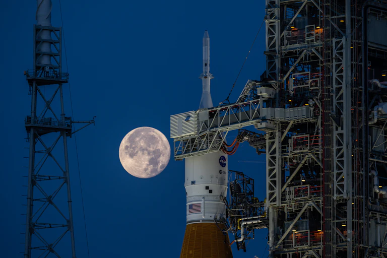 La pleine lunde derrière la coiffe de la fusée SLS sur sa rampe de lancement.