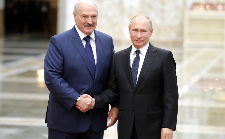 Two men in suits shaking hands.