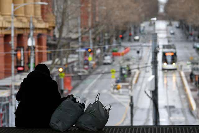 Person with their possessions in shopping bags looks at deserted Melbourne street