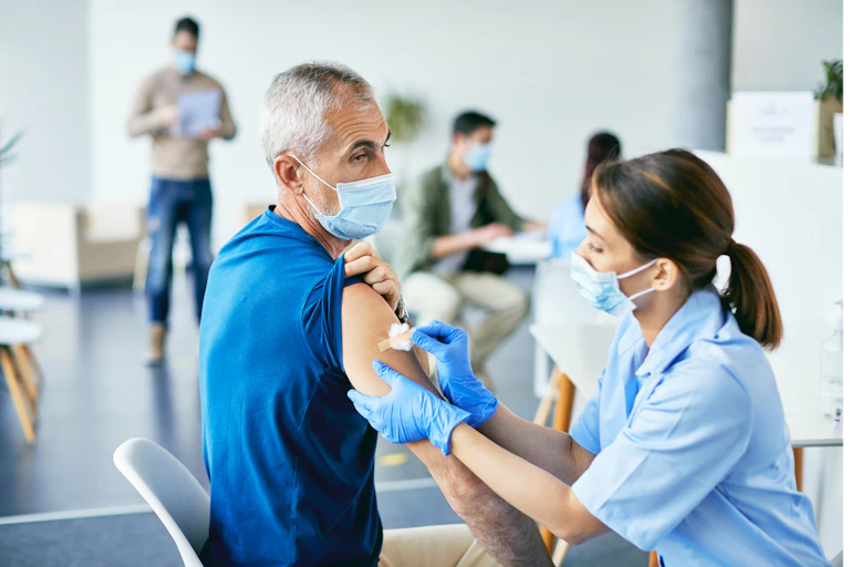 A nurse affixes a bandaid to a man's upper arm.