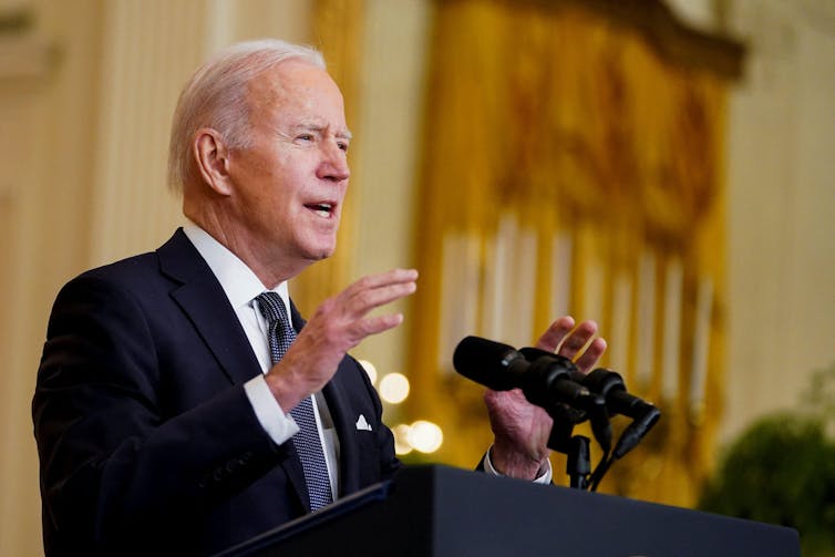 Joe Biden in a suit at a microphone.