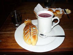 Un pan dulce servido al lado de una bebida morada.