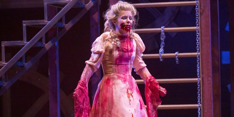 Woman in a white dress covered in blood.