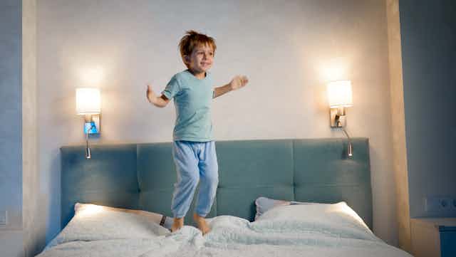 A child jumps on the bed at nighttime.