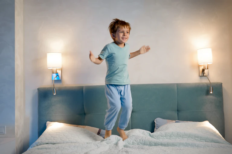 A child jumps on the bed at nighttime.