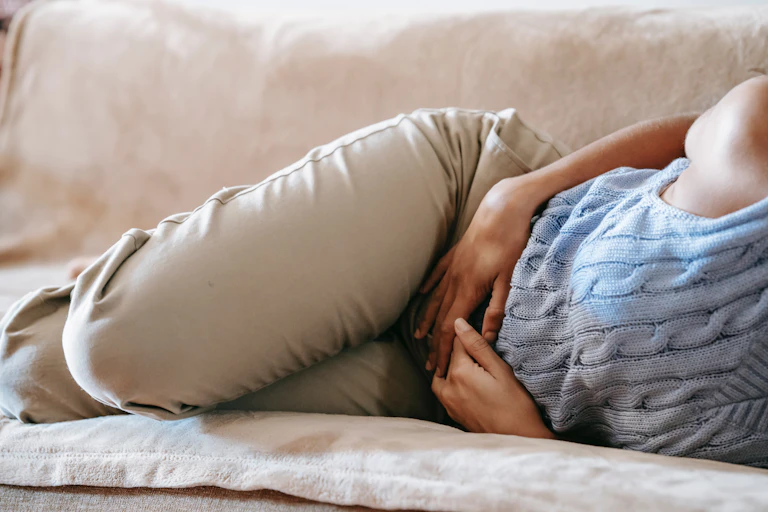 A woman grasps her stomach in discomfort.