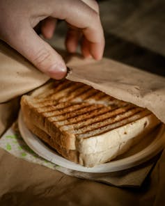 Takeaway toasted sandwich in a brown bag.