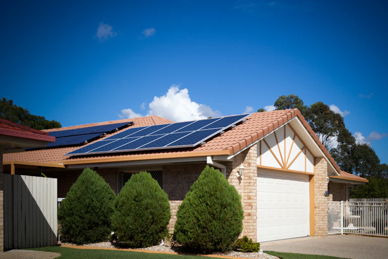home with manicured shrubs and solar panels on roof