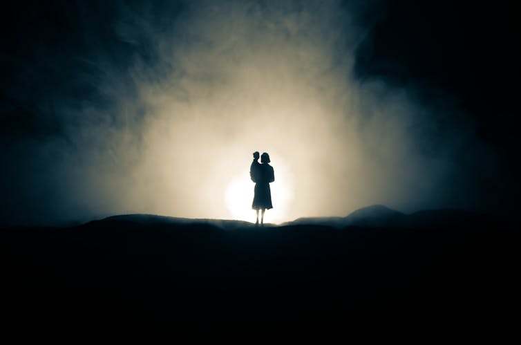 A woman and child are seen in silhouette against a white background.