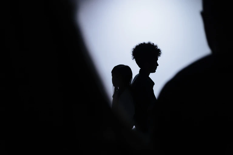 Two children are seen in silhouette against a white background.