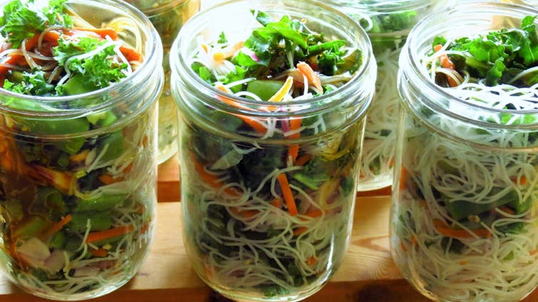 Jars of noodle salad with fresh vegetables.