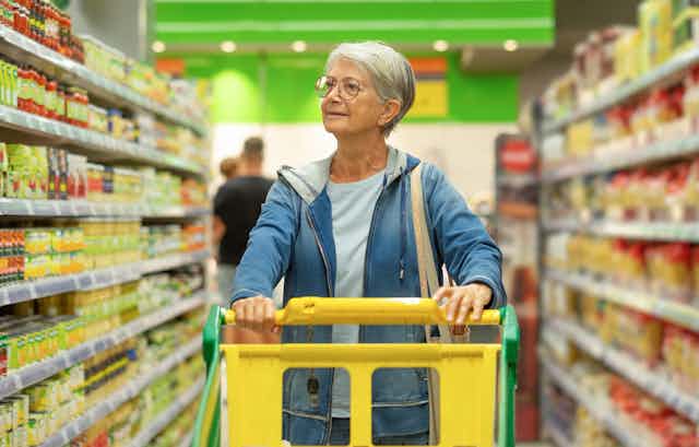 Woman with trolley, looking at supermarket shelves