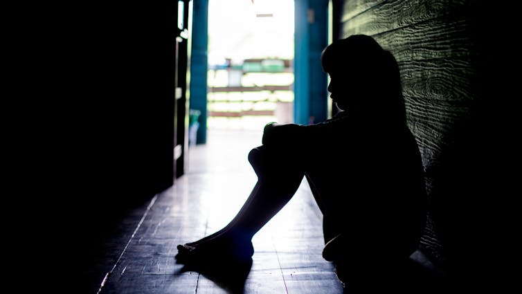 A child sits in a hallway.