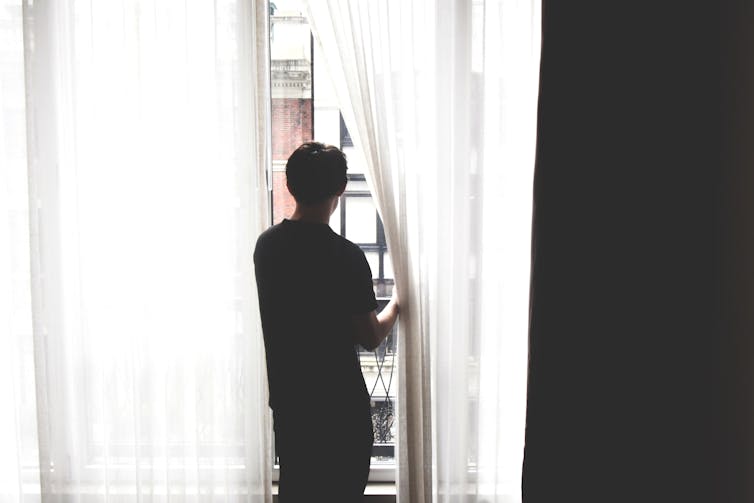 Person looks out of their apartment window