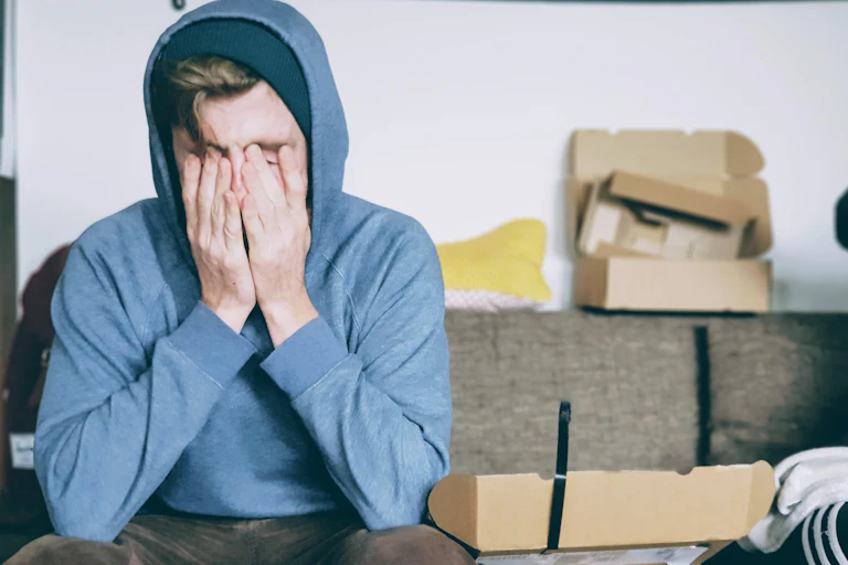 Man in hoodie covers his eyes