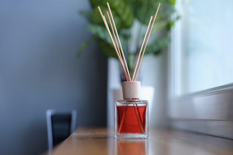 an amber coloured diffuser with several wooden sticks on a windowsill
