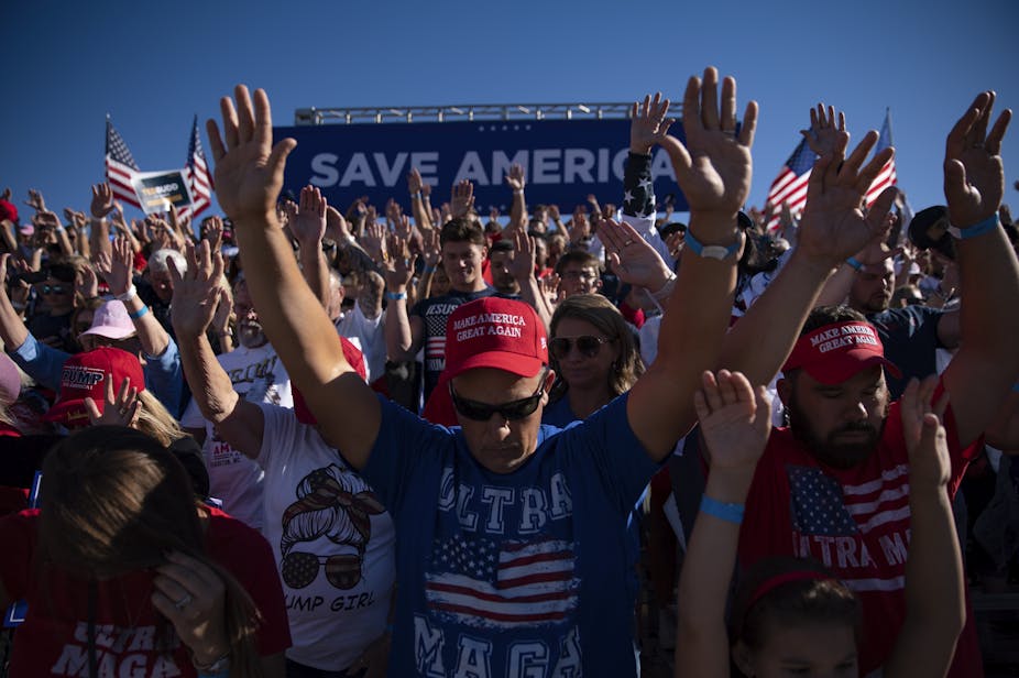 Personnes en tshirts et casquettes en l'honneur de Trump en train de prier pendant un meeting électoral