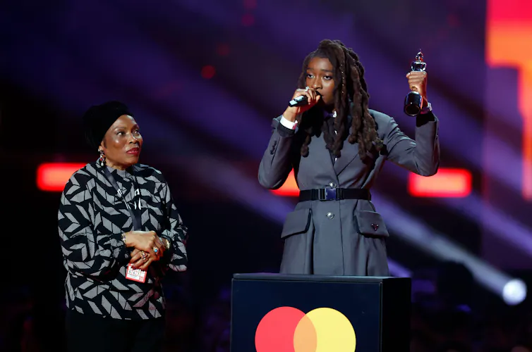 Rapper Little Simz on a stage receiving a Brit award.