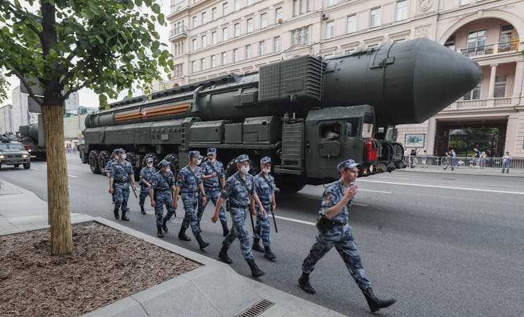Russian police march in front of a Russian strategic nuclear missile RS-24 Yars moving through a street ahead of a night rehearsal of the Victory military parade on Red Square, in Moscow, June 2020.