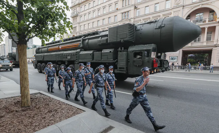 Russianpolice march in front of a Russian strategic nuclear missile RS-24 Yars which moves along a street prior to a night rehearsal of the Victory military parade in the Red Square, in Moscow, June 2020.