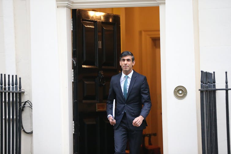 Rishi Sunak walking out of Number 11 Downing Street with a folder under his arm.