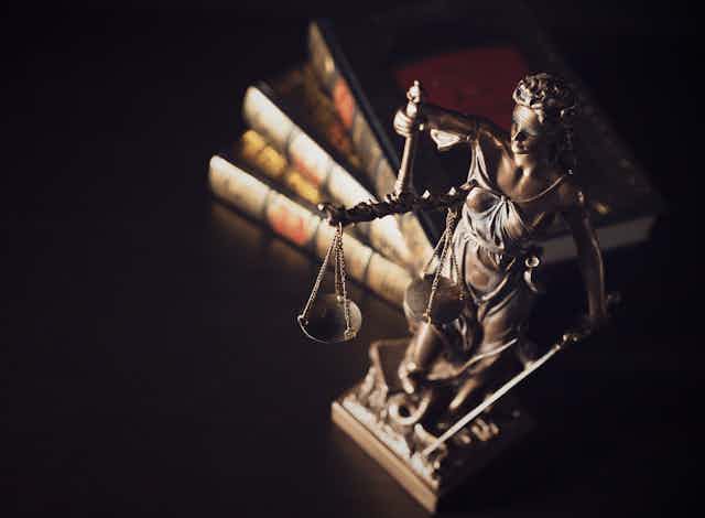 small stature of lady justice in front of law books