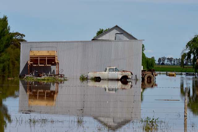 Old machinery and cars sit in floodwaters in rural Victoria.