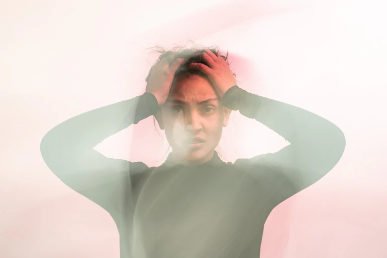 woman holds head in frustration and confusion, obscured by fog