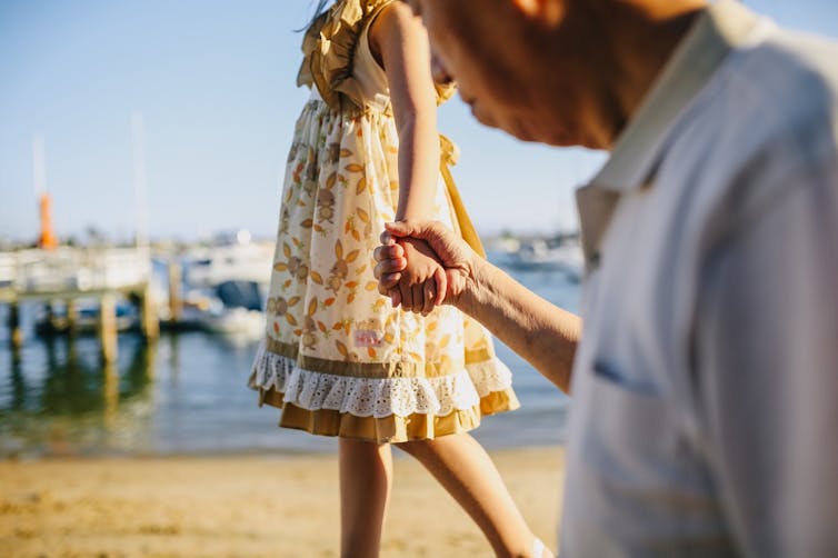 Grandfather holding granddaughter's hand while walking