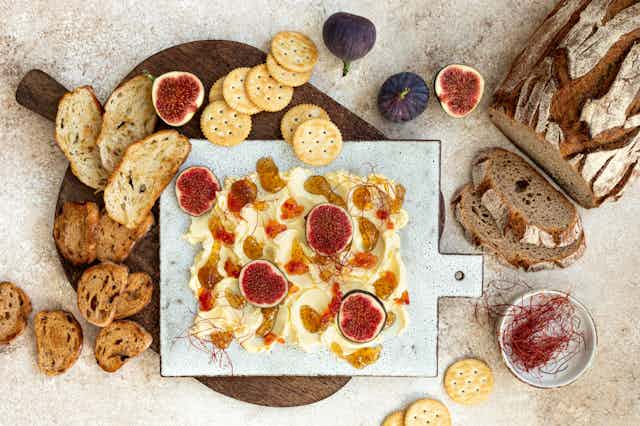 A butter board surrounded by various baguettes and crackers.