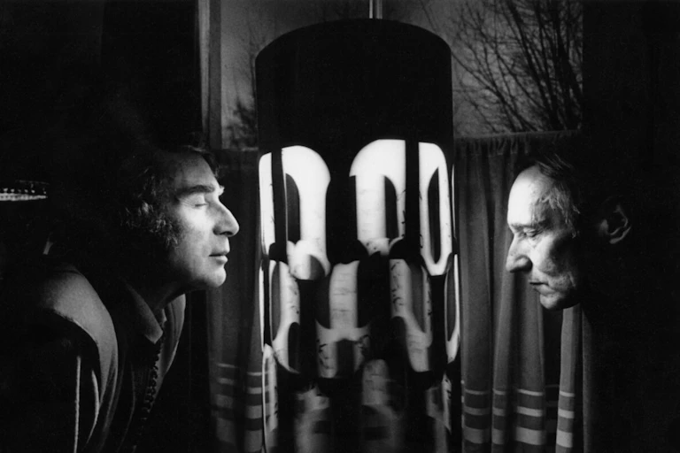 Two men standing in front of a machine with eyes closed.